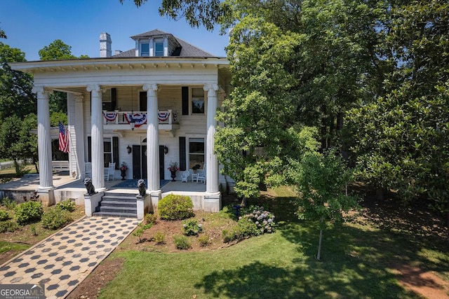 greek revival inspired property featuring a porch, a balcony, and a front lawn