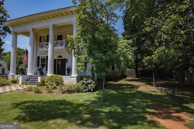 view of front of home with a balcony and a front yard