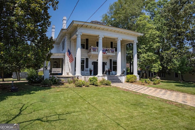 neoclassical home with a balcony, covered porch, and a front yard