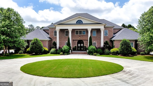 neoclassical home featuring a front yard