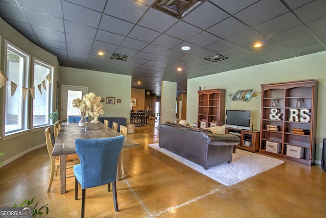 living room featuring concrete floors and a paneled ceiling