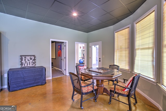 dining area with concrete floors, a drop ceiling, and a healthy amount of sunlight