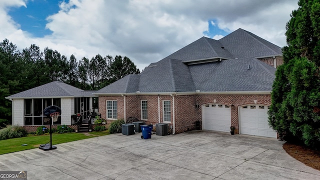 back of property with a garage, a sunroom, and a yard