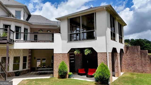 rear view of property with a balcony, a patio, and a lawn