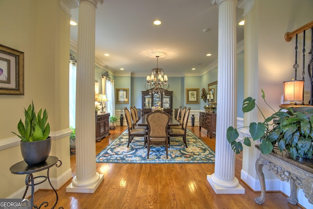 dining space with decorative columns, ornamental molding, a notable chandelier, and wood-type flooring