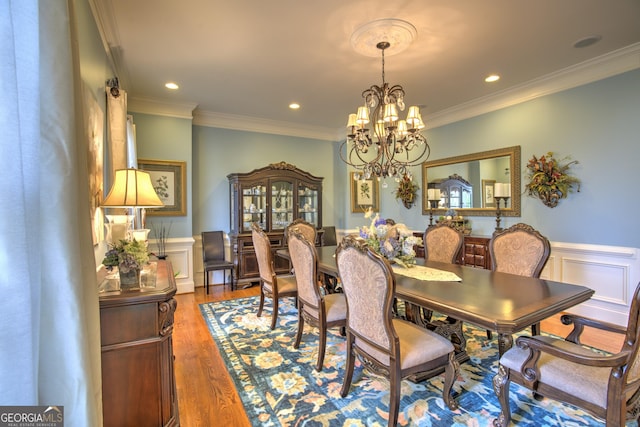 dining room featuring wood-type flooring, ornamental molding, and a chandelier