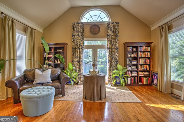 sitting room with crown molding, light hardwood / wood-style flooring, and lofted ceiling