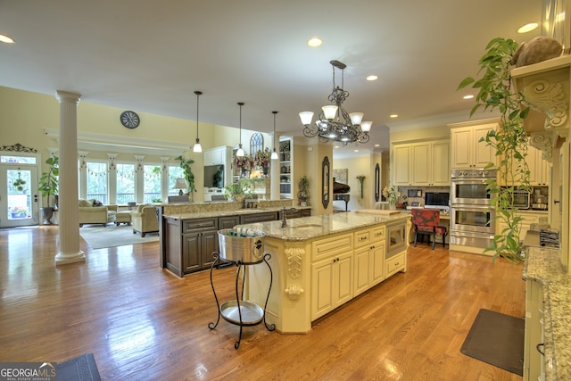 kitchen with decorative columns, decorative light fixtures, stainless steel appliances, and a spacious island