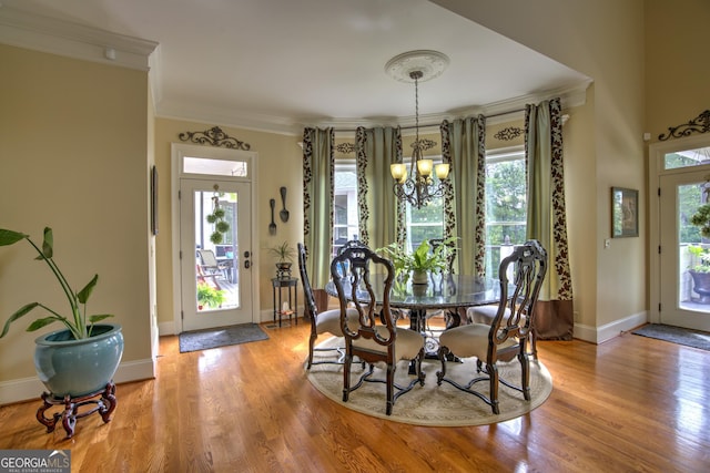 dining area with crown molding, light wood-type flooring, and a chandelier