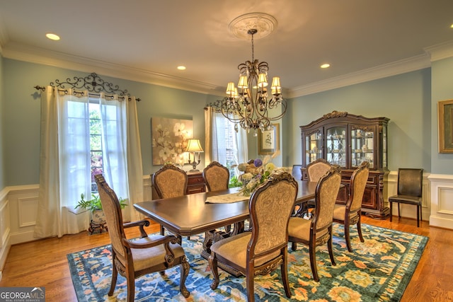 dining area featuring light wood-type flooring, crown molding, and a notable chandelier