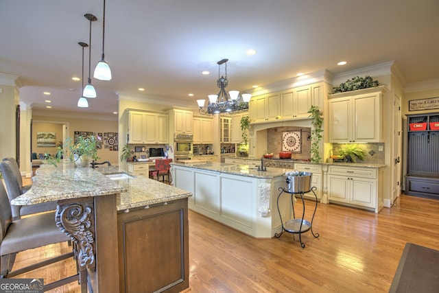 kitchen featuring a large island with sink, pendant lighting, a breakfast bar, and light stone counters