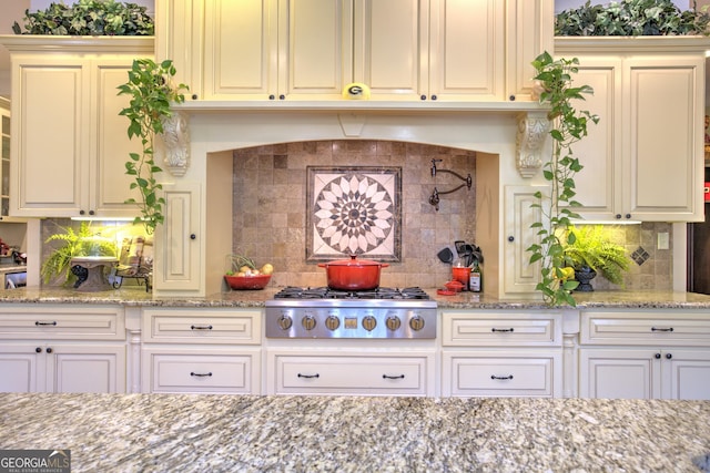 kitchen featuring backsplash, light stone countertops, and stainless steel gas cooktop