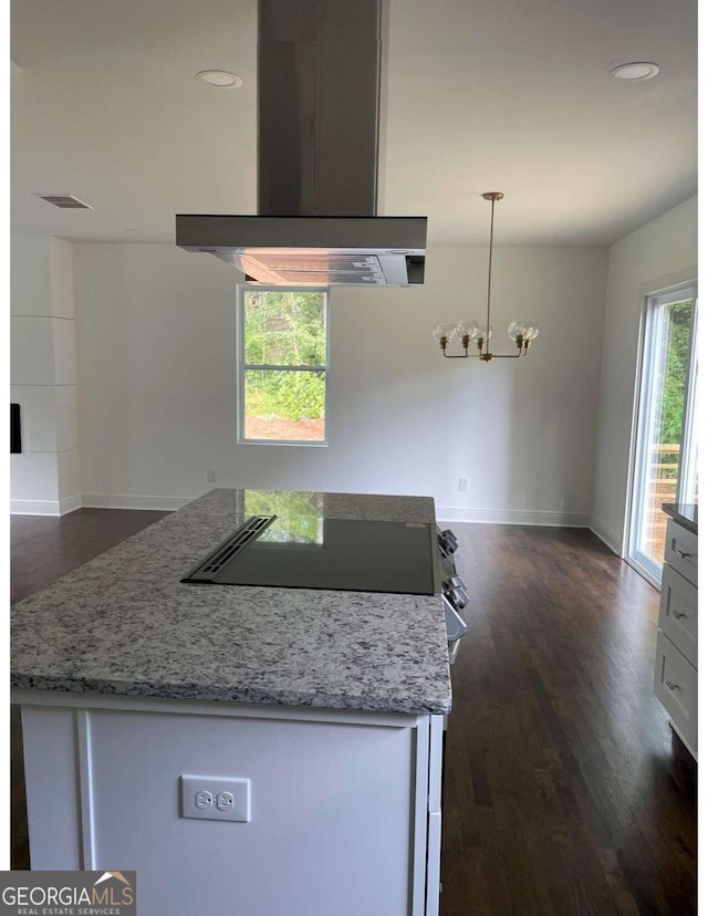 kitchen with light stone countertops, hanging light fixtures, dark hardwood / wood-style floors, and ventilation hood