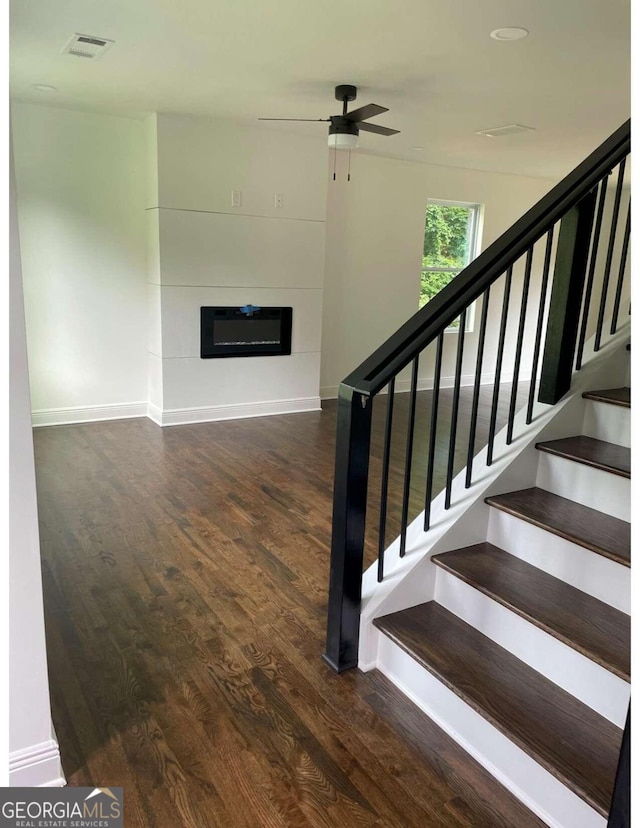 staircase with ceiling fan and wood-type flooring