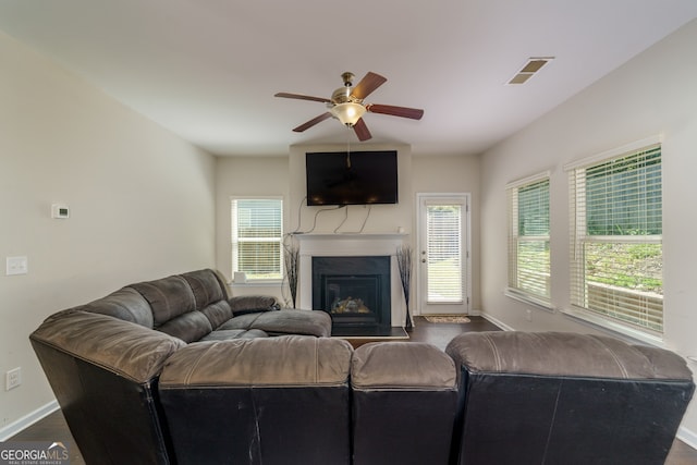 living room featuring dark wood-type flooring, a healthy amount of sunlight, and ceiling fan