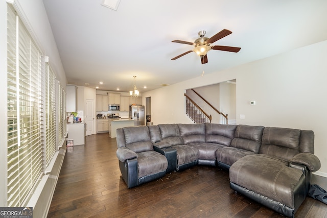 living room with ceiling fan with notable chandelier and dark hardwood / wood-style flooring