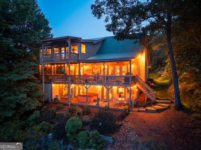 back house at dusk with a patio area and a balcony