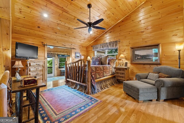 bedroom with wooden walls, high vaulted ceiling, access to outside, and wood finished floors