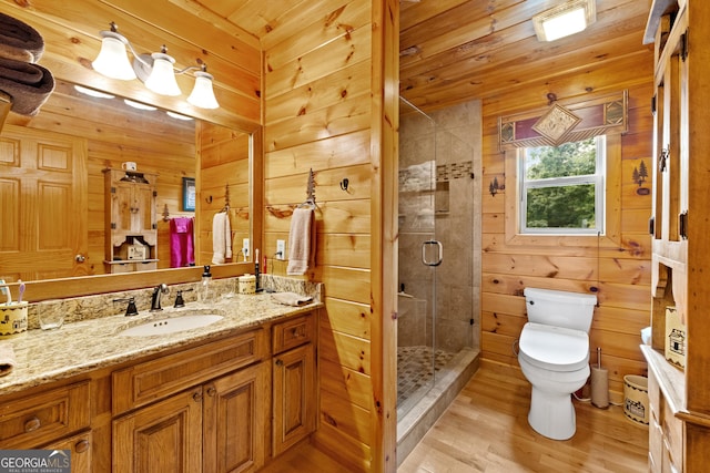 bathroom with a shower stall, wood walls, wood finished floors, vanity, and toilet