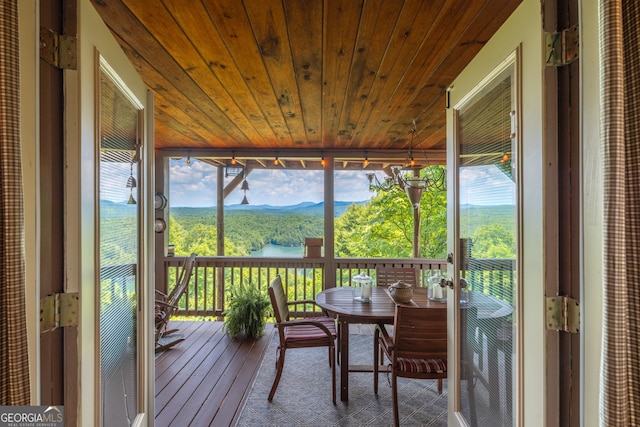 sunroom featuring a mountain view and wood ceiling