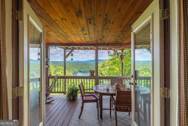 sunroom featuring outdoor dining area, a mountain view, and plenty of natural light