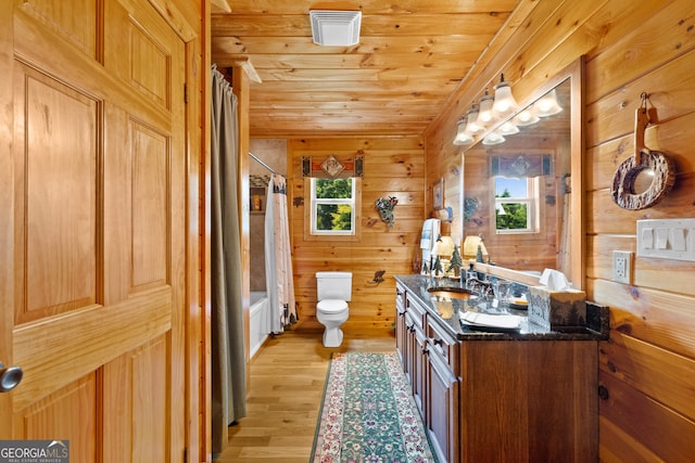 bathroom with wooden walls, vanity, toilet, shower / bathtub combination with curtain, and wood finished floors