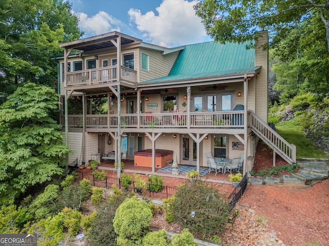 back of property featuring a hot tub, a deck, and a patio area