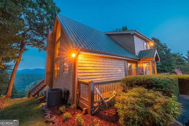 view of home's exterior featuring a standing seam roof, central AC unit, metal roof, a mountain view, and stairway