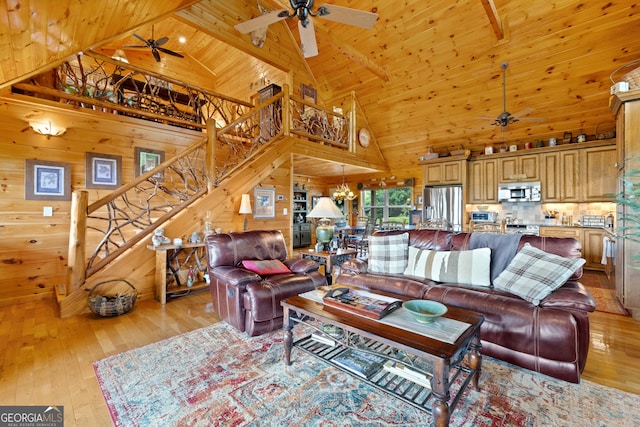 living room with wood walls, ceiling fan with notable chandelier, wooden ceiling, high vaulted ceiling, and light hardwood / wood-style flooring