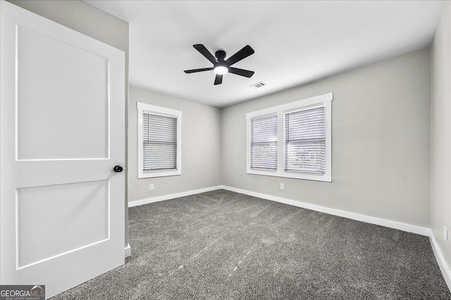 empty room with ceiling fan and dark colored carpet