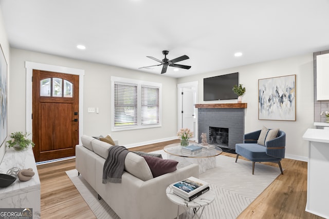 living room with light hardwood / wood-style floors, a brick fireplace, and ceiling fan