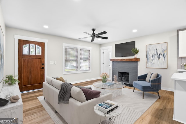 living room with ceiling fan, a fireplace, and light wood-type flooring