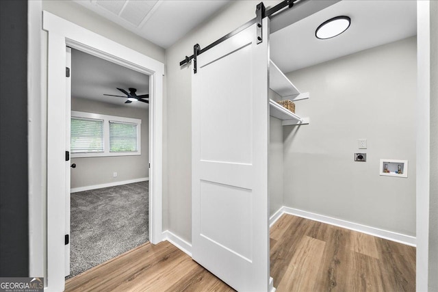 washroom featuring electric dryer hookup, washer hookup, wood-type flooring, and a barn door