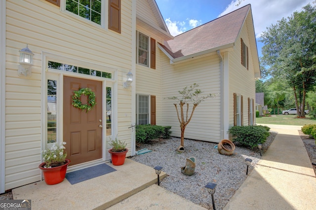 doorway to property with roof with shingles