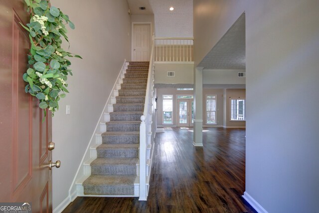 entrance foyer with a towering ceiling and dark hardwood / wood-style flooring