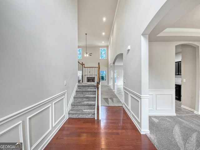 stairs featuring hardwood / wood-style flooring, ceiling fan, a towering ceiling, and ornamental molding