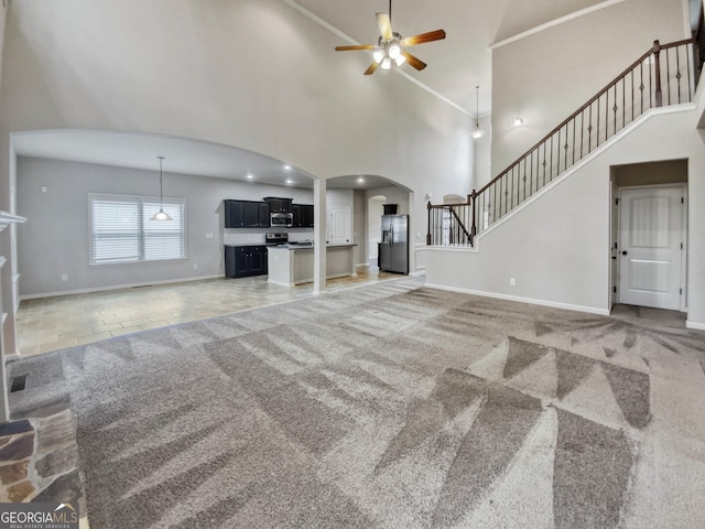 unfurnished living room with carpet flooring, high vaulted ceiling, and ceiling fan