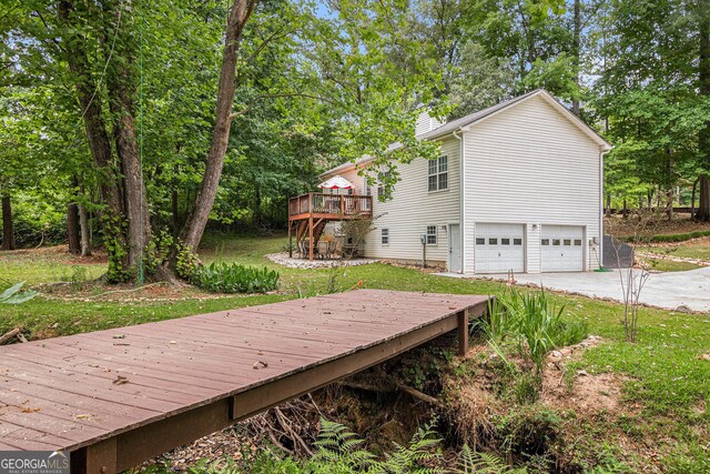 104 Streambank Ct, Temple, GA 30179 - wooden deck with an attached garage, driveway, and view of scattered trees