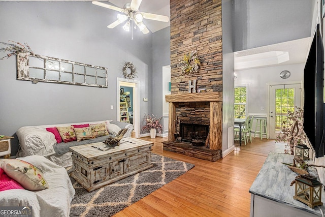 104 Streambank Ct, Temple, GA 30179 - living area with a towering ceiling, light wood-style flooring, a ceiling fan, and a stone fireplace