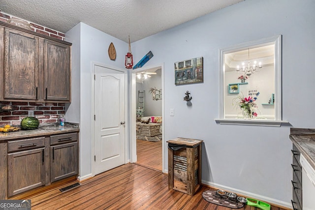 104 Streambank Ct, Temple, GA 30179 - kitchen with wood finished floors, dark brown cabinets, a textured ceiling, a chandelier, and baseboards