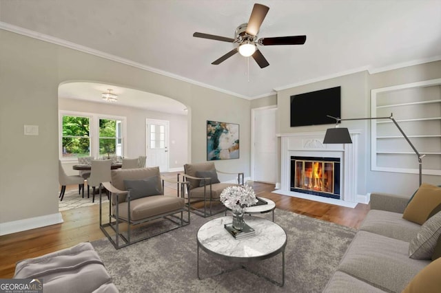 living room with ceiling fan, wood-type flooring, and crown molding