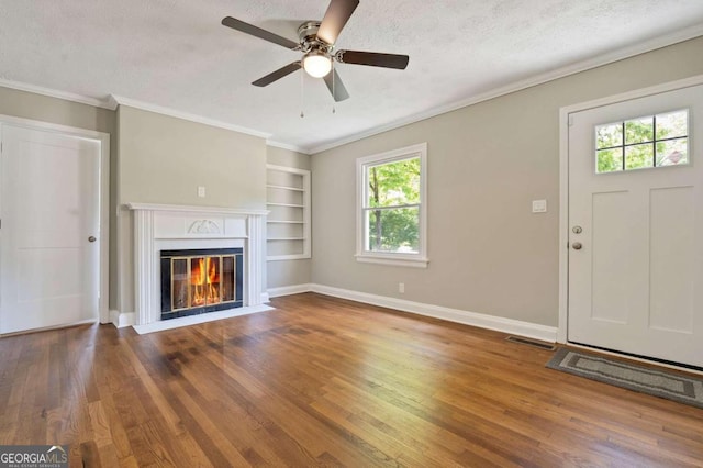 unfurnished living room with dark hardwood / wood-style floors, ceiling fan, ornamental molding, and a textured ceiling