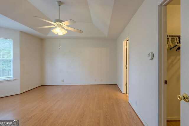 empty room featuring light hardwood / wood-style flooring, a raised ceiling, and ceiling fan