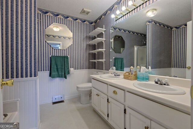 bathroom featuring toilet, vanity, and a shower with door