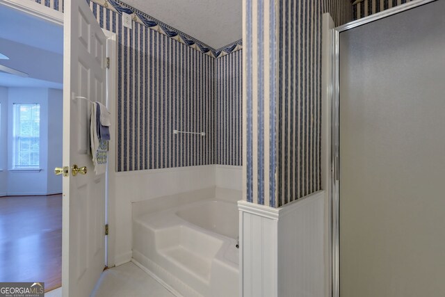 bathroom with a textured ceiling and separate shower and tub