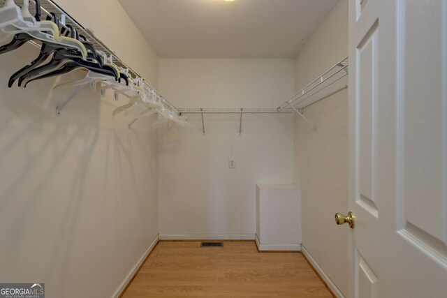 walk in closet with light hardwood / wood-style flooring