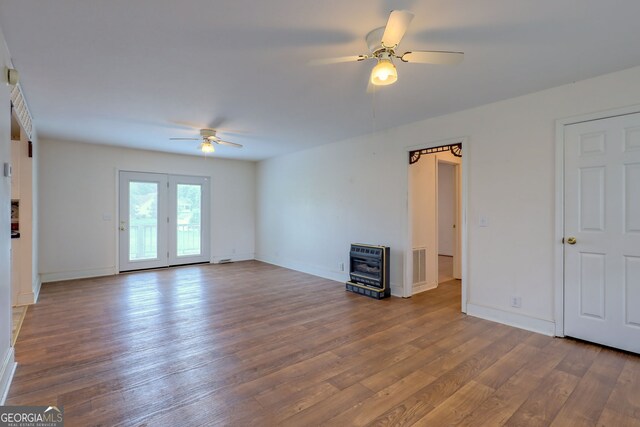 unfurnished living room with hardwood / wood-style flooring, heating unit, and ceiling fan