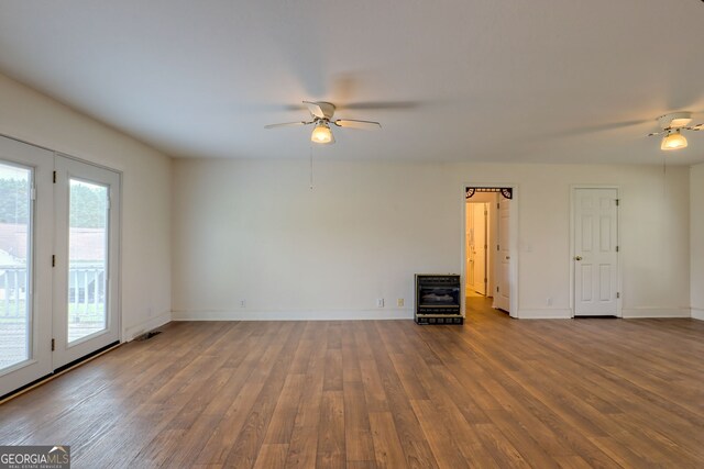 unfurnished room with hardwood / wood-style floors, heating unit, and ceiling fan