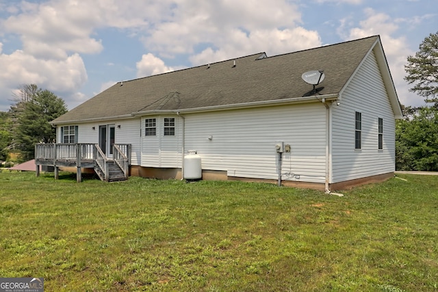 back of property featuring a wooden deck and a yard