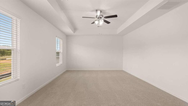 unfurnished room featuring a raised ceiling, ceiling fan, and light carpet